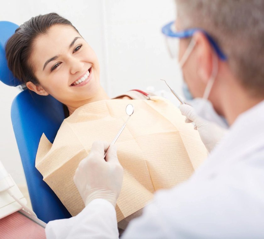 A woman sitting in the dentist chair while being examined by an expert.