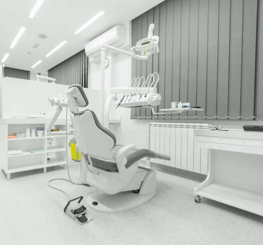 A dentist 's office with a chair and equipment.