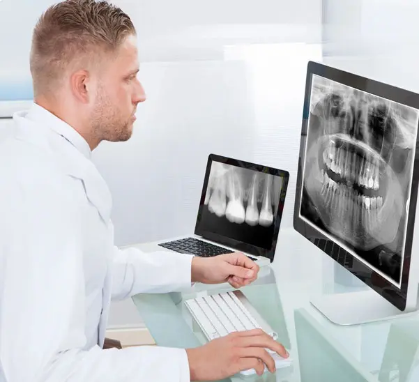 A man sitting at his computer looking at an x-ray.